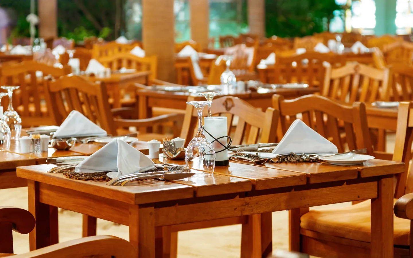 Salle de restaurant aux tables de bois dressées et serviettes pliées · photo d'illustration