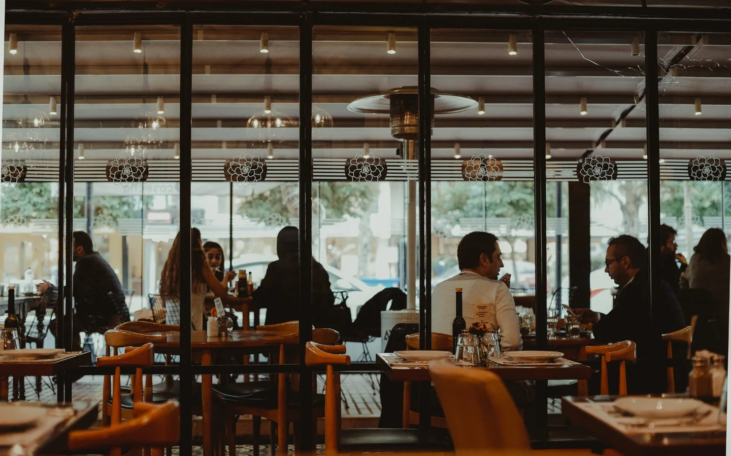Terrasse vitrée d'un restaurant avec ses clients attablés · photo d'illustration